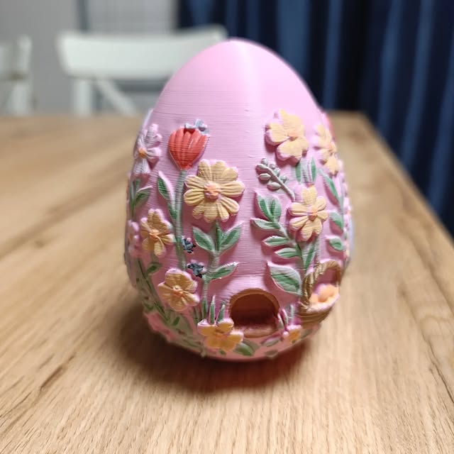 Różowa pisanka pokryta ręcznie malowaną łąką kwiatów.