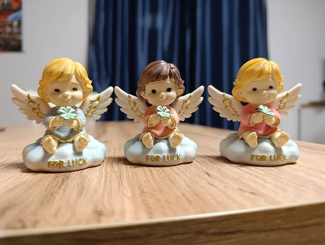 Trio aniołków na chmurkach z czterolistną koniczyną — na szczęście.