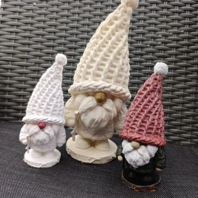 Trio skrzatów — w bieli, kremie i bordowej czapce.